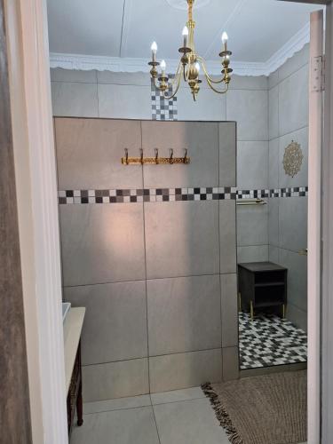 a bathroom with a chandelier and a tile wall at 21on2nd Avenue in Tzaneen