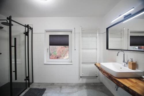 a white bathroom with a sink and a window at Blackhillhouse - Moderne Auszeit im Harz in Osterode
