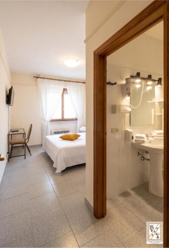 ein Schlafzimmer mit Bett und ein Badezimmer mit Waschbecken in der Unterkunft Le Volpaie in San Gimignano