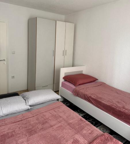 two beds in a room with white cabinets and red sheets at Apartman HODŽIĆ in Sarajevo
