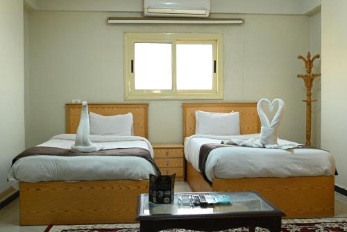 a room with two beds and a table and a window at فندق شهرزاد - Shahrazad Hotel in Banī ‘Aţīyah