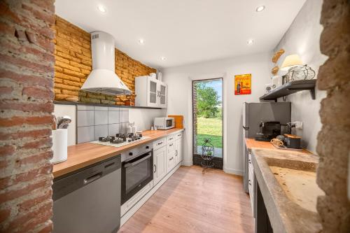 a kitchen with white appliances and a large window at Pigeonnier de charme in Villefranche-de-Lauragais