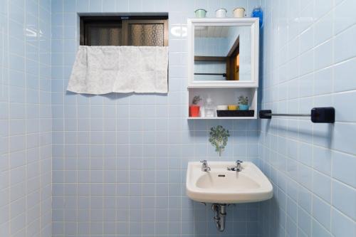 a blue tiled bathroom with a sink and a mirror at Green Hights Residence-107 in Naha