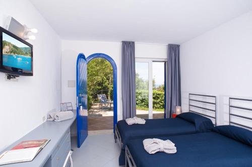 a bedroom with two beds and a tv and a window at Hotel della baia - Negombo Parco Termale in Lacco Ameno