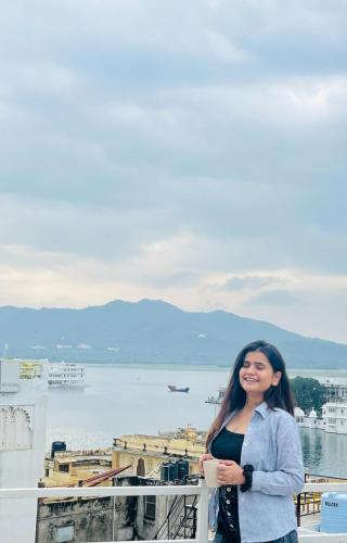 a woman standing on a balcony overlooking the water at Old Skool Udaipur - 20 Meter From Lake in Udaipur