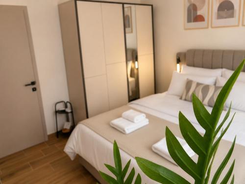 a bedroom with a white bed with a plant at Sea & Sun Luxury Apartment in Alexandroupoli