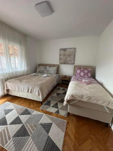 a bedroom with two beds and a rug at Etno Kuća Jaćimović 1 in Pranjani