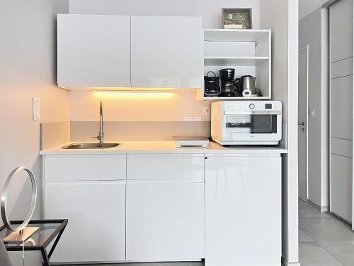 a kitchen with white cabinets and a microwave at Studio rez-de-jardin la Baule proche centre Pornichet in La Baule