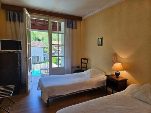 a hotel room with two beds and a window at Hostellerie de La Poste in Oust