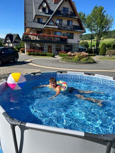 a young boy in a swimming pool with a ball at Willa Pod Kozińcem in Czarna Góra
