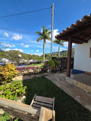 a wooden bench sitting in the grass next to a building at Casa Trindade in Tiradentes
