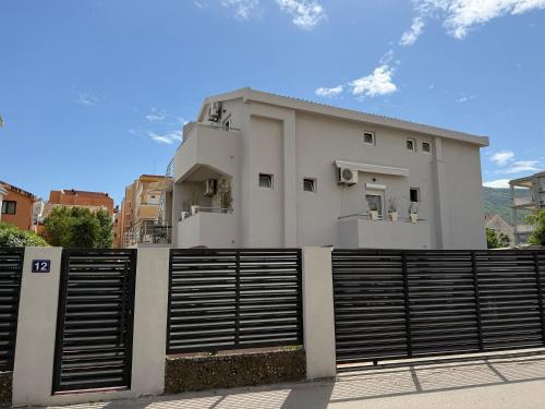 a white house with a fence in front of it at Guest House Jasna in Budva