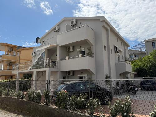 a white building with a car parked in front of it at Guest House Jasna in Budva