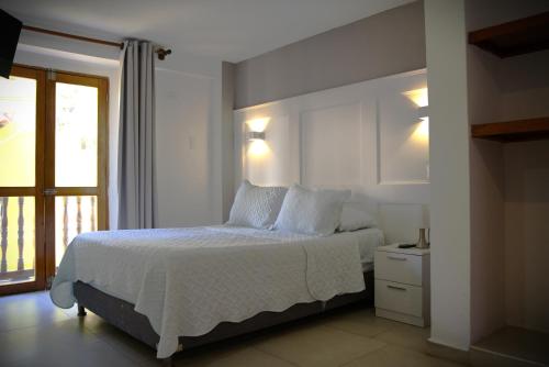 a bedroom with a bed with white sheets and a window at Akel House Hotel - Getsemaní - Cartagena in Cartagena de Indias