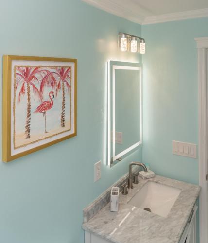 ein Badezimmer mit Waschbecken und einem Bild von Palmen in der Unterkunft Flamingo Inn in Fort Myers Beach