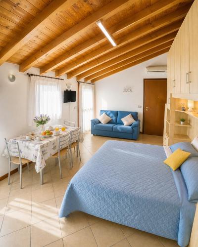 a bedroom with a blue bed and a table at Residence Mediterraneo - Agenzia Cocal in Caorle