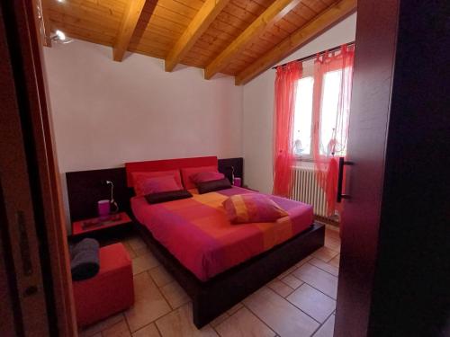 a bedroom with a bed with red sheets and a window at Casina Rossa in Ballabio