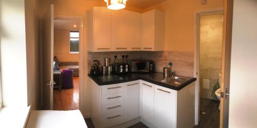 a kitchen with white cabinets and a black counter top at Ty Mynydd Lodge Holiday Home in Cardiff