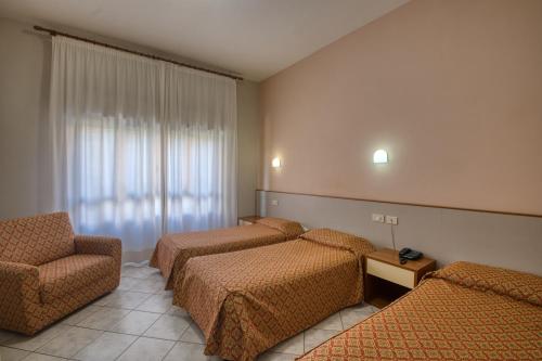 a hotel room with three beds and a chair at Albergo La Posta Arezzo in Badia Al Pino