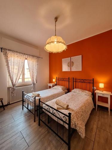 two beds in a bedroom with orange walls at B&B near Lake Como - Close to train & bus - Breakfast included in Valmadrera