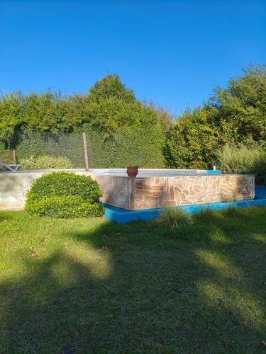a stone retaining wall in a yard next to a field at Camiare Aparts in Villa General Belgrano