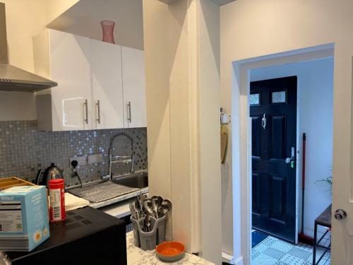 a kitchen with a sink and a black door at Sunshine apartment in Maidstone