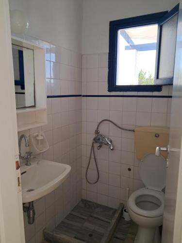 a bathroom with a toilet and a sink and a window at Pyrgis Glyfades studios in Glifades