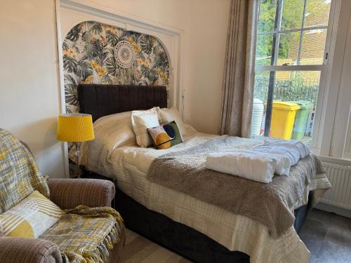 a bedroom with a bed and a chair and a window at Sunshine apartment in Maidstone
