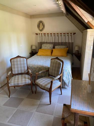 a bedroom with a bed and two chairs at La Petite Bergère in Saint-Méloir-des-Ondes