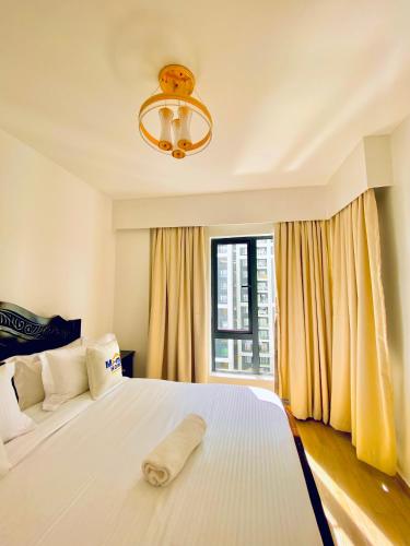 a bedroom with a large white bed with a window at Nairobi Comfort Suites in Nairobi