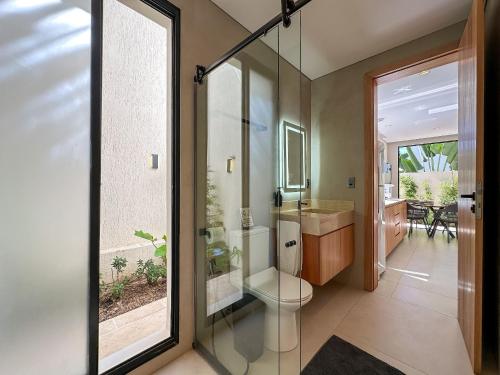 a bathroom with a toilet and a glass shower at Chalé by Vila Manga Rosa in Pipa