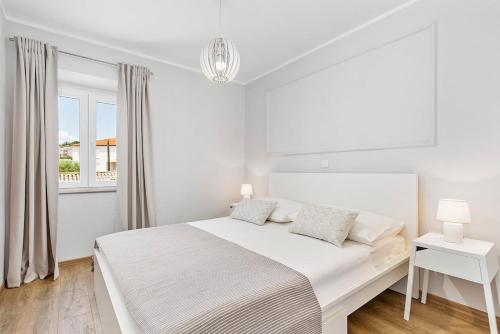 a white bedroom with a bed and a window at Apartment Katja in Vantačići