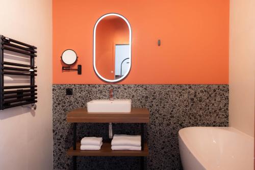 ein orangefarbenes Badezimmer mit Waschbecken und Spiegel in der Unterkunft Hotel 2M, The Originals Relais in Saint-Rambert-sur-Loire