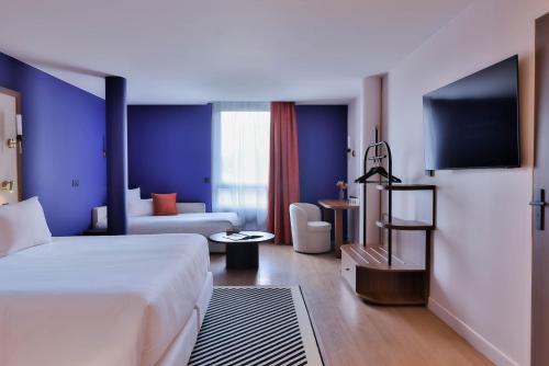ein Hotelzimmer mit Bett und Fernseher in der Unterkunft Hotel 2M, The Originals Relais in Saint-Rambert-sur-Loire