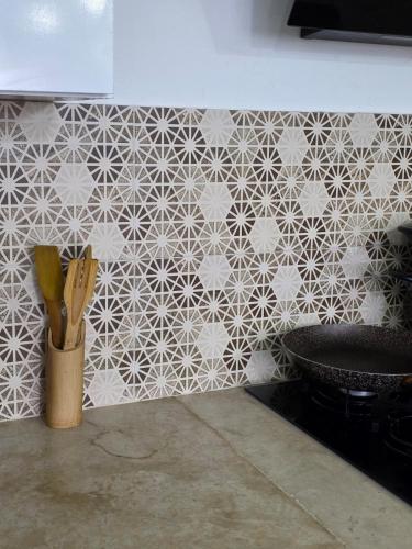 a kitchen with a tile wall with a container of knives at Dar Julia Seaview Apartment in Mahdia