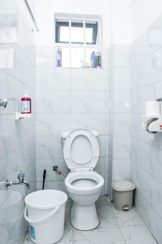 a white bathroom with a toilet and a window at The Bird House in Munyu