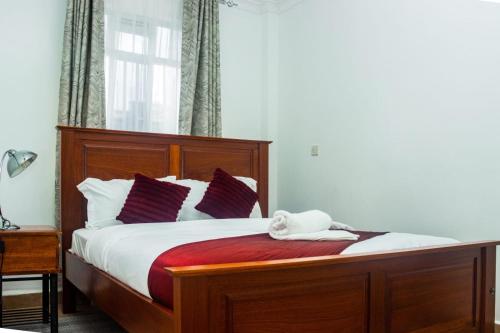 a bedroom with a large wooden bed with red and white pillows at The Bird House in Munyu