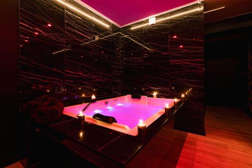 a pink bath tub with candles in a room at 007 Loveroom Secrète Jacuzzi privé Cinéma 4K in Courcouronnes