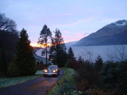a car driving down a road next to a lake at Corriegour Lodge Hotel in Spean Bridge