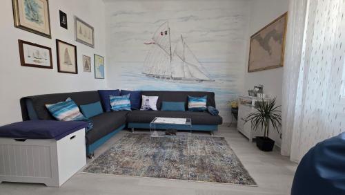 a living room with a blue couch and a boat on the wall at Giuly Sole e Sale in Le Grazie