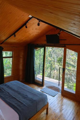 a bedroom with a bed in a room with windows at Glamping villeta campo heliconias in Villeta