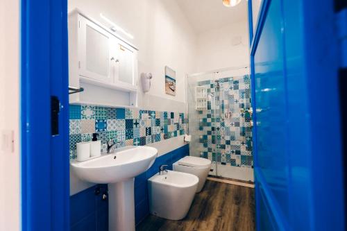 ein blau-weißes Badezimmer mit Waschbecken und Toilette in der Unterkunft A Patedda in Favignana