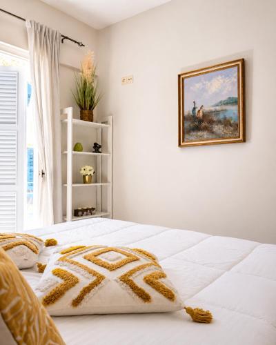 a white bed in a bedroom with a picture on the wall at Veneziana Liston view apt in Corfu