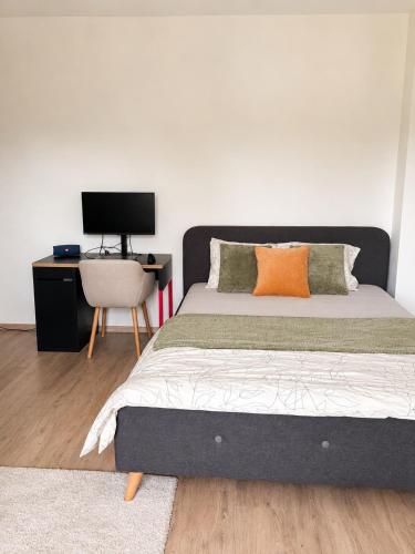 a bedroom with a bed with an orange pillow and a desk at Moderní studio s terasou v klidné lokalitě in Jihlava
