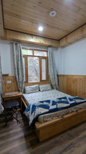 a bedroom with a bed and a desk and a window at Kunzang Homestay in Shalkār