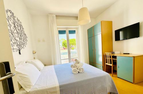 a small bedroom with a bed and a desk and a window at Hotel Solitude in Riccione