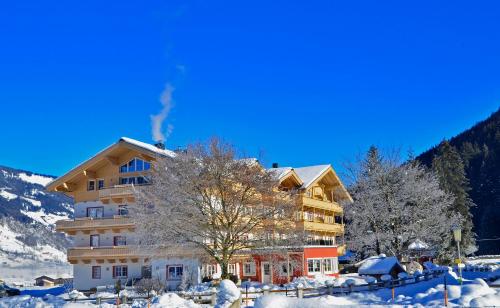 a large building with snow on the ground at Hotel Grundlhof in Bramberg am Wildkogel