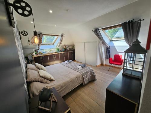 a bedroom with a large bed and a red chair at chambres de La Maillette in Locminé