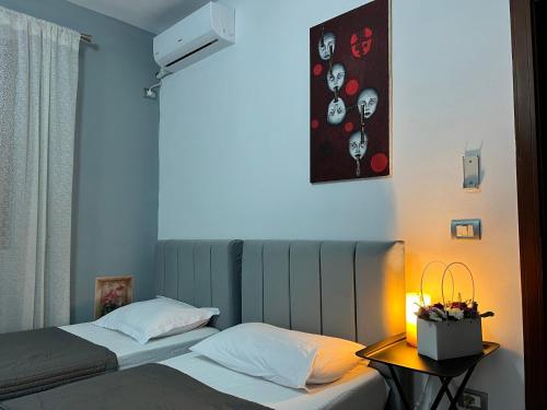 Host Apartments في شكودر: سريرين في غرفة مع مصباح على طاولة