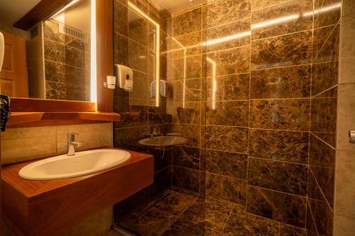 a bathroom with a sink and a mirror at Hotel Lotus Spa&Sport Akyaka in Akyaka